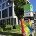 Roland Mair hält eine Regenbogenflagge vor dem DATEV-Gebäude