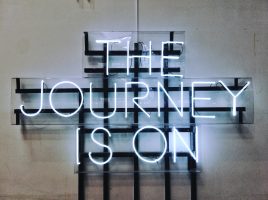 Auf dem Bild steht in Leuchtbuchstaben: The Journey is on